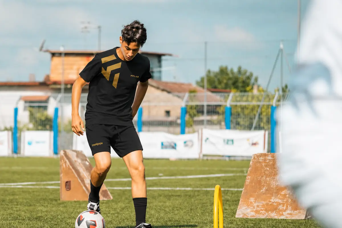 Giovane calciatore in controllo palla sul campo allo stage Fitlab Future