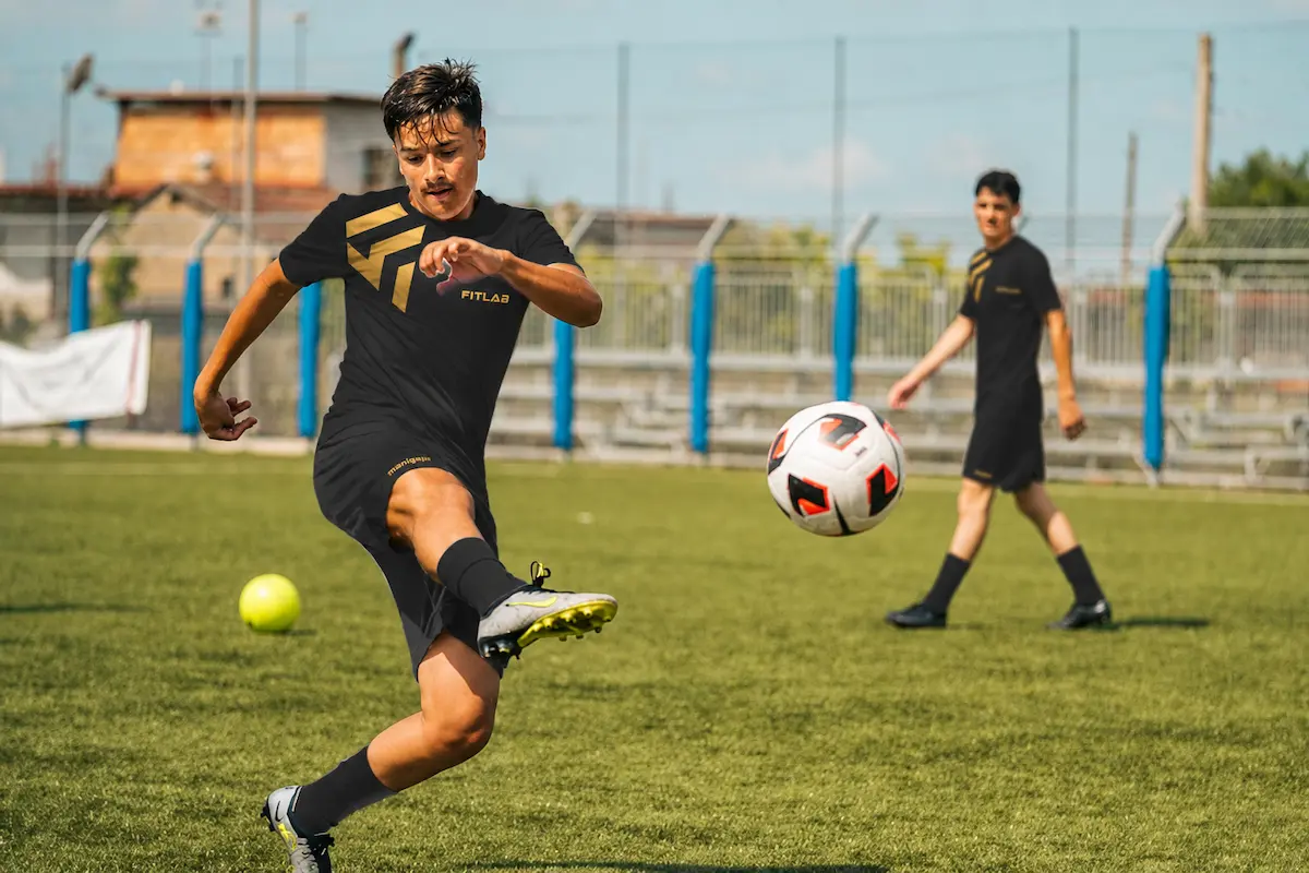 Giovane calciatore calcia il pallone in campo durante una situazione di gioco, stage Fitlab Future